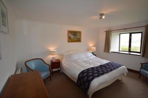 a bedroom with a bed and a table and a window at Diubaig House in Edinbane