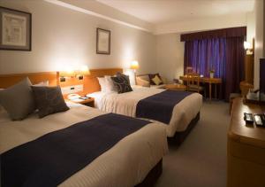 a hotel room with two beds and a desk at Kanazawa New Grand Hotel Premier in Kanazawa