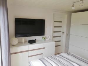 Schlafzimmer mit einem Flachbild-TV und einem Bett in der Unterkunft Kuldigas Holiday House in Kuldīga