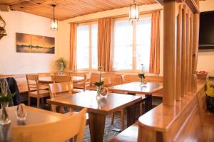 un restaurante con mesas y sillas de madera y ventanas en Hotel Toggenburgerhof, en Kirchberg