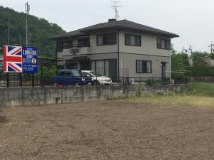 dom z samochodami zaparkowanymi przed nim w obiekcie E.English Guest House w mieście Sekimachi