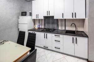 a kitchen with white cabinets and a table and a sink at Apartment with 2 bedroom near Opera House Gorodotska 27 str with parking in Lviv