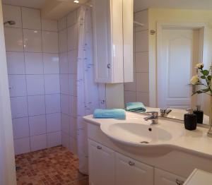 La salle de bains blanche est pourvue d'un lavabo et d'une douche. dans l'établissement Ferienwohnung Graf Düne, à Karlshagen