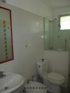a white bathroom with a toilet and a sink at Maga in Piriápolis