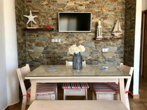 mesa de comedor con sillas y TV en una pared de piedra. en Apartamento Triana II Bolonia, Tarifa en Bolonia
