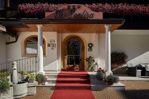 un tapis rouge menant à la porte d'entrée d'un bâtiment dans l'établissement Mountain B&B - La Scalira, à Corvara in Badia