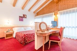1 dormitorio con 1 cama y escritorio con ordenador en Pineta Pastry Hotel, en Rocca Pietore