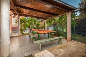 une table et des bancs en bois sous une pergola en bois dans l'établissement Apartment CHUDE, à Pula