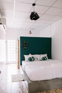 ein großes Bett in einem Zimmer mit grüner Wand in der Unterkunft Baannokhook Home&Cafe in Surat Thani