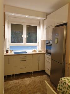 eine Küche mit weißen Schränken und einem Kühlschrank aus Edelstahl in der Unterkunft Metropol Lux apartment Belgrade Vracar in Belgrad