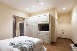 sypialnia z łóżkiem, telewizorem i białymi szafkami w obiekcie Agave in Città w mieście Livorno