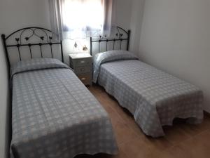 2 Einzelbetten in einem Zimmer mit Fenster in der Unterkunft Alojamiento La Fuente in Fuenteheridos