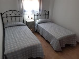 two twin beds in a room with a window at Alojamiento La Fuente in Fuenteheridos
