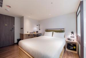 a bedroom with a large white bed and a desk at City Suites - Main Station in Taipei