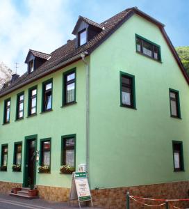 バッハラッハにあるFerienwohnungen Kachelの前の看板のある緑の家