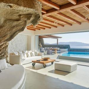 a living room with white furniture and a swimming pool at Cavo Tagoo Mykonos in Mýkonos City