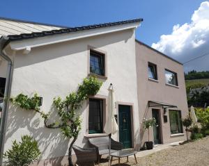 een wit huis met een patio en een parasol bij Zur alten Rebe Ferienhaus und Weingut in Konz