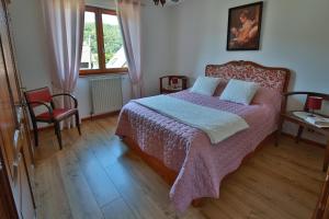 um quarto com uma cama, uma cadeira e uma janela em MAISON DE TATIE em Luttenbach-près-Munster
