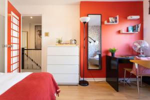 1 dormitorio con paredes rojas, escritorio y espejo en Tower Bridge Rainbow Suites, en Londres 47 fotos más