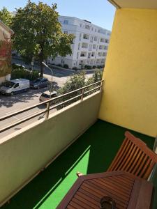 a balcony with a wooden chair and a green floor at Apartment Augsburg Mitte in Augsburg