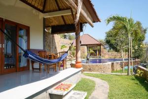 a hammock on the porch of a house with a pool at Bamboo Bali Hill Bungalows in Amed