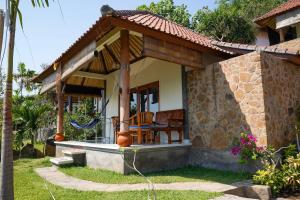 a house with a pavilion with a table and chairs at Bamboo Bali Hill Bungalows in Amed