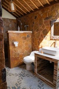 a stone bathroom with a toilet and a sink at Bamboo Bali Hill Bungalows in Amed +60 photos