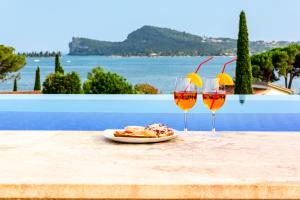 two glasses of wine and a plate of food on a table at Lamasu RioVerde - Lago di Garda in San Felice del Benaco
