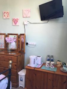 a bedroom with a wooden dresser with a tv on the wall at Weyside House in Weymouth