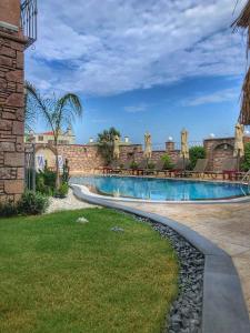 a swimming pool in a yard next to a brick wall at Sukha Cunda Otel in Cunda