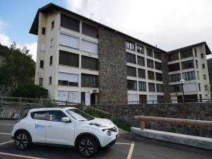 une voiture blanche garée dans un parking en face d'un bâtiment dans l'établissement El Tarter-Vacances Pirinenca, au Tarter