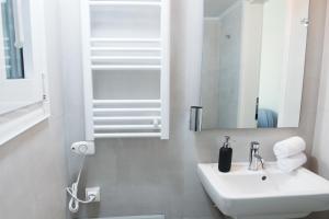 a white bathroom with a sink and a mirror at Piraeus Seaview Elegant Apartments in Piraeus