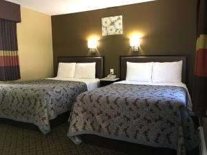 a hotel room with two beds and two lamps at Scottish Inns Milford in Milford