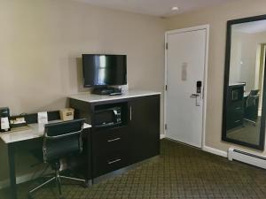 ミルフォードにあるScottish Inns Milfordのデスク、テレビ、ドレッサーが備わるホテルルームです。