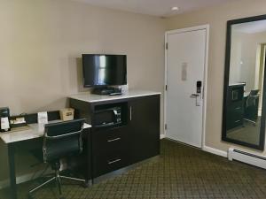 a hotel room with a desk with a television on a dresser at Scottish Inns Milford in Milford
