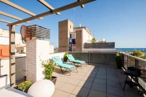 un patio en la azotea con sillas y toldo en un edificio en Terrassa de Mar Apartment, en Masnou