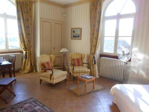 a bedroom with two chairs and a bed and windows at Chateau des Poccards in Hurigny