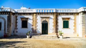 un grande edificio bianco con finestre verdi e una porta di Casale Cappuccio Apartments a Ostuni