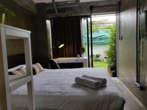 a bedroom with two beds and a desk and a window at THE HOG in Bangkok Yai