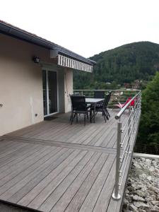 una terraza de madera con mesa y sillas. en La maison des savoyards en Husseren-Wesserling