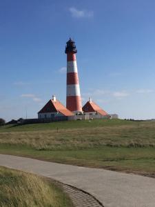 um farol vermelho e branco sentado em cima de um campo em Nordseeperle Husum em Husum