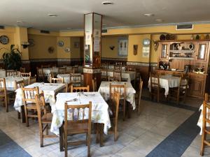 un restaurante con mesas y sillas con mantel blanco en HOSTAL EL ESCUDO, en Cilleruelo de Bezana