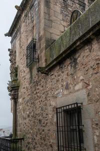 ein altes Backsteingebäude mit einem Fenster und einem Zaun in der Unterkunft Domus Seleqtia Plaza de Santiago in Cáceres