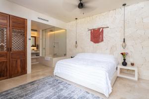 a bedroom with a white bed and a stone wall at Villa LaGú Masterpiece Tulum Jungle 5BR Pool & Spa in Tulum +33 photos