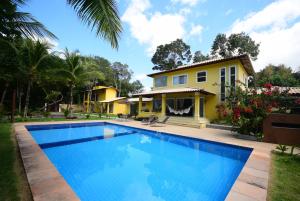 a villa with a swimming pool in front of a house at Quintas do Arraial Guest House in Arraial d'Ajuda
