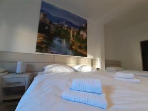 Una cama blanca con dos toallas encima. en Guest House Vanja, en Mostar