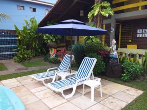 two chairs and an umbrella on a patio at Otima casa, perto de tudo!! in Porto De Galinhas