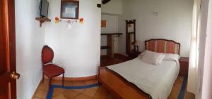 um quarto com uma cama e uma cadeira em Casona Santo Domingo em Villa de Leyva