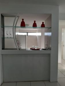 a kitchen with glass shelves with red vases on it at Park Way Home Service in Recife