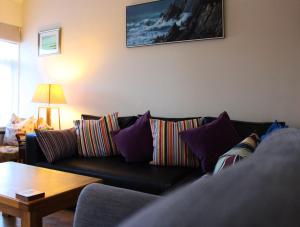 sala de estar con sofá negro y almohadas coloridas en The Beachfront Retreat, en Rush